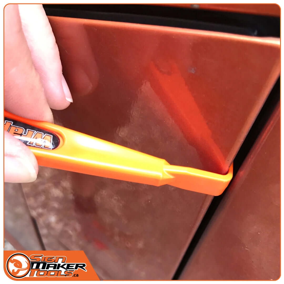 Hand using WrapStick HangLoose tool to tuck vinyl wrap into a vehicle trim line